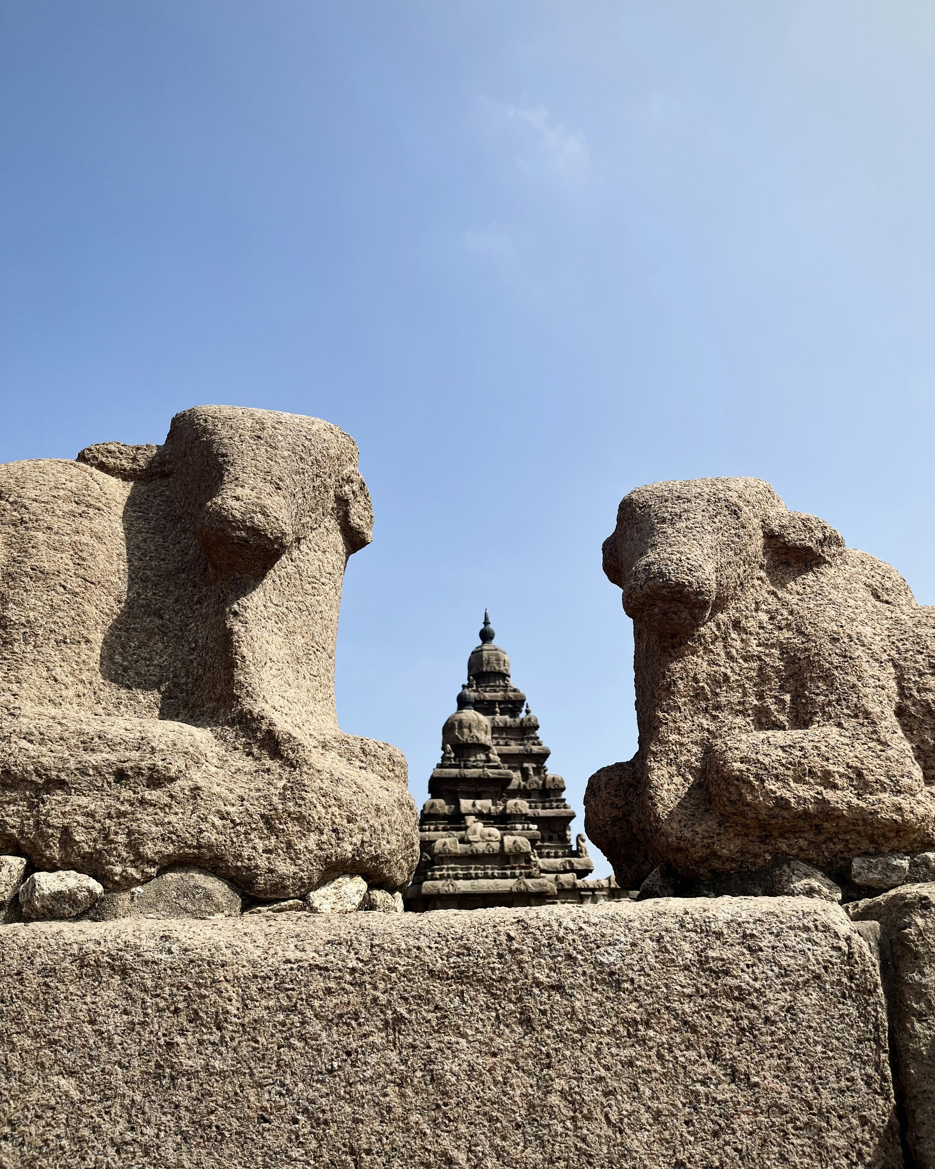 eine Gruppe von Steinskulpturen, die auf einer Steinmauer sitzen