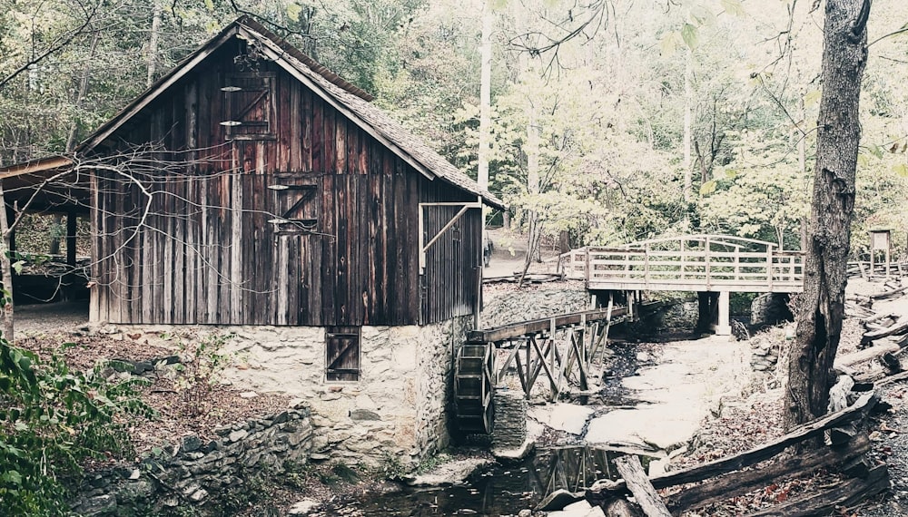 a wooden building in the woods next to a bridge
