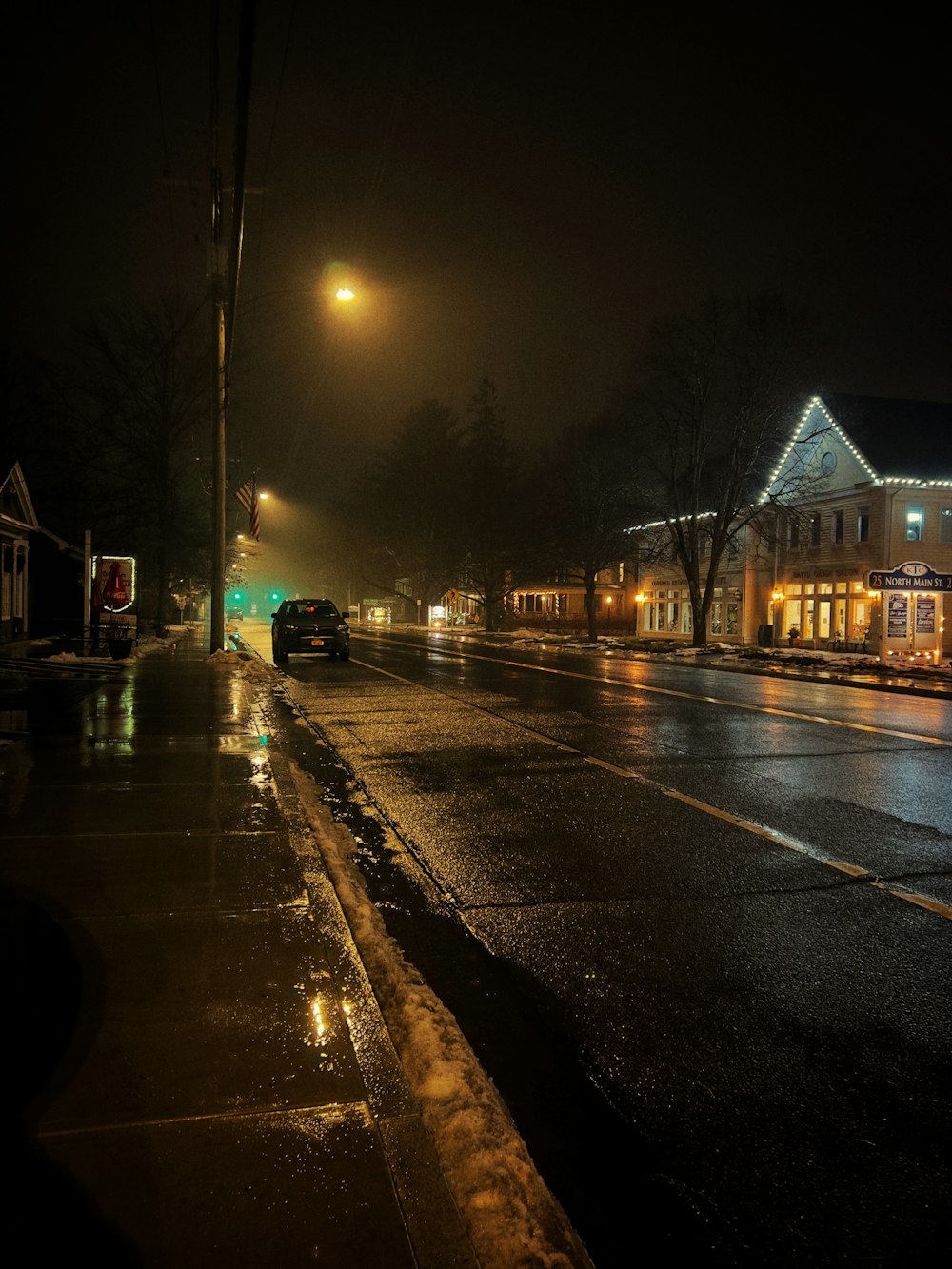 a city street at night with cars parked on the side of the road