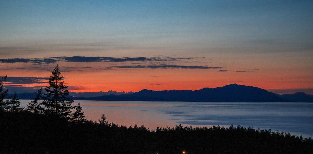 a sunset over a lake with mountains in the background