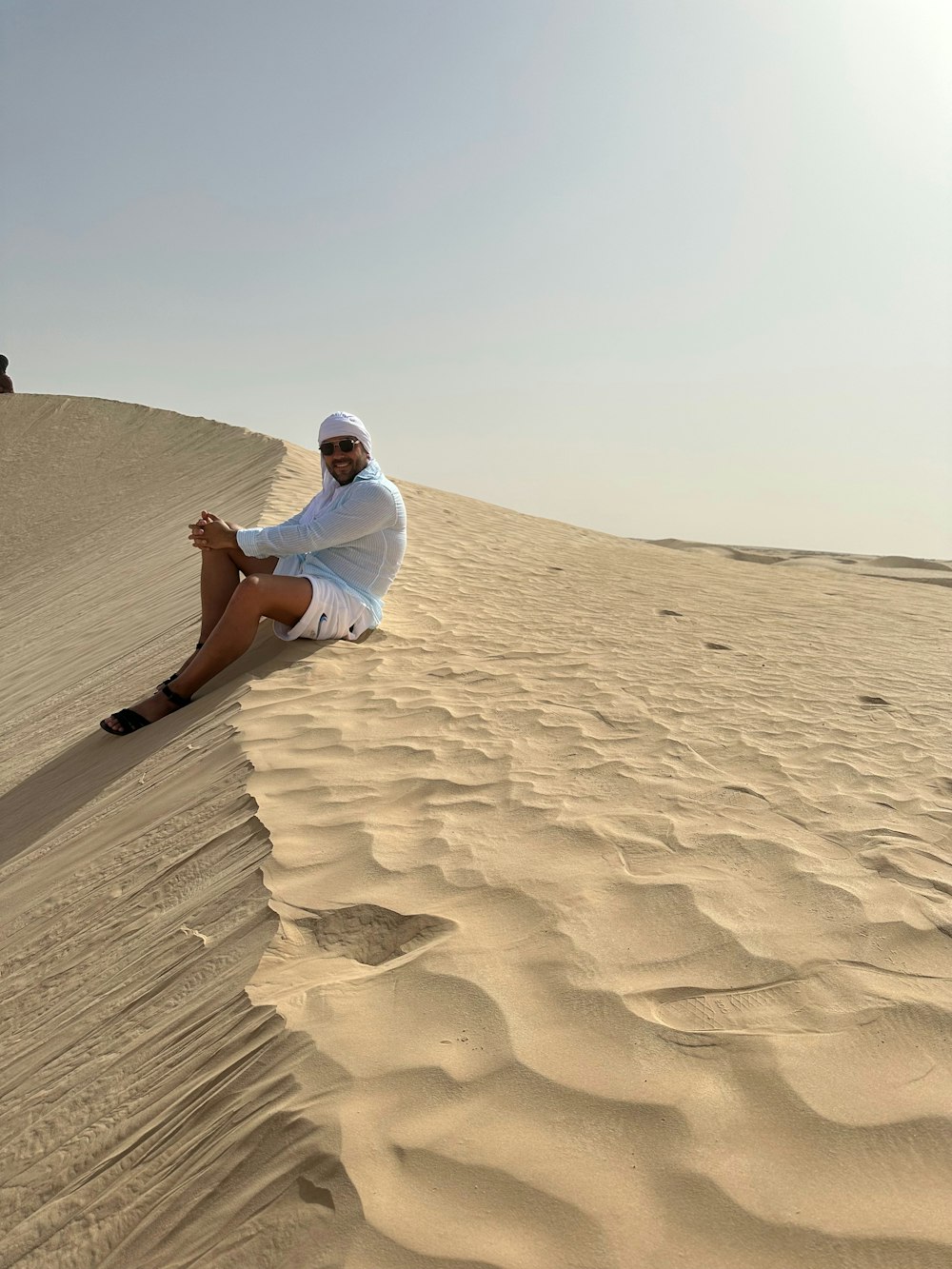 a man sitting on top of a sandy dune