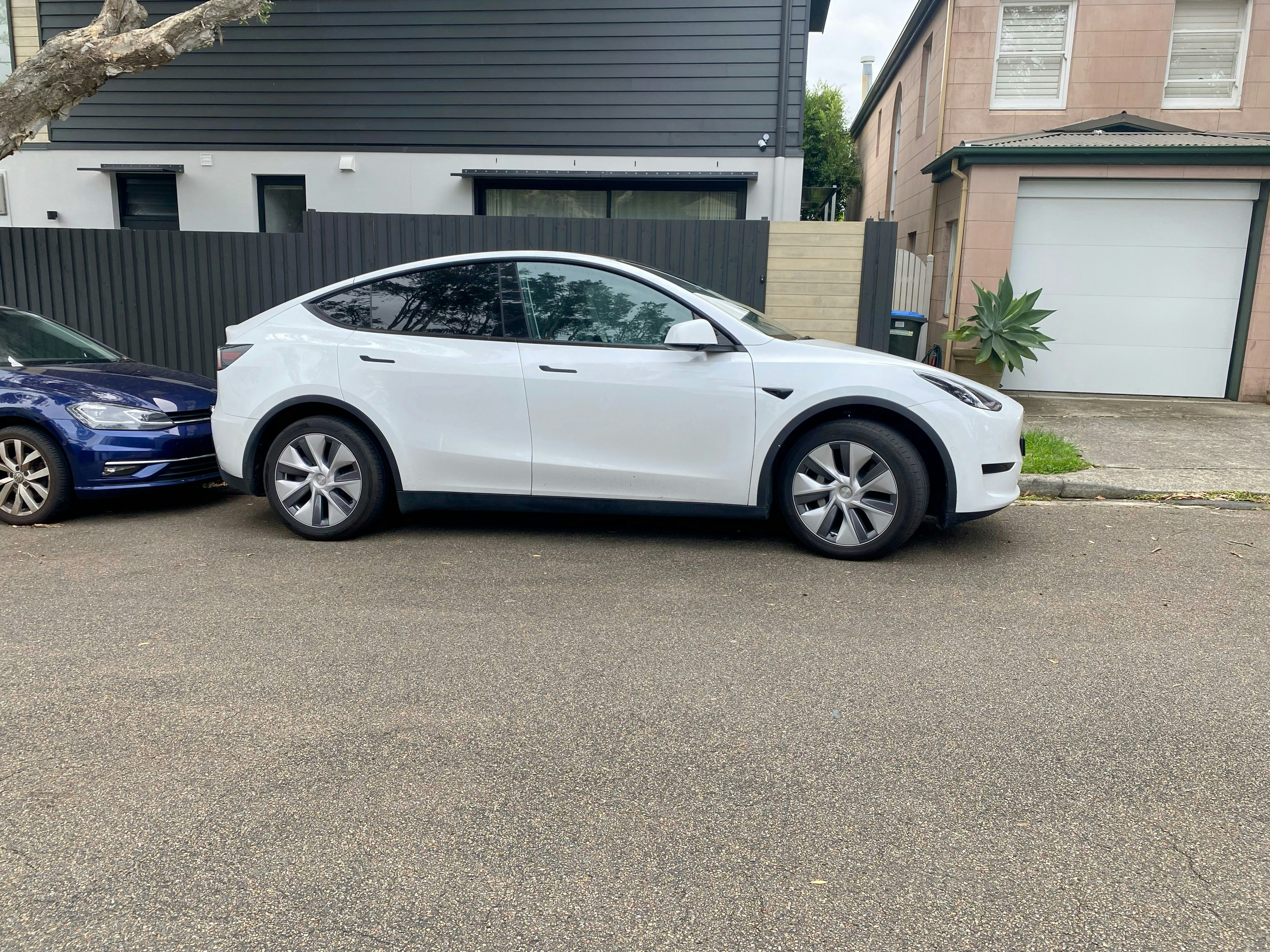 Used electric car plugged into a home charger in a driveway