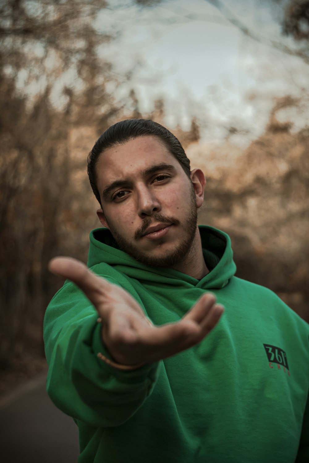 a man in a green hoodie making a hand gesture