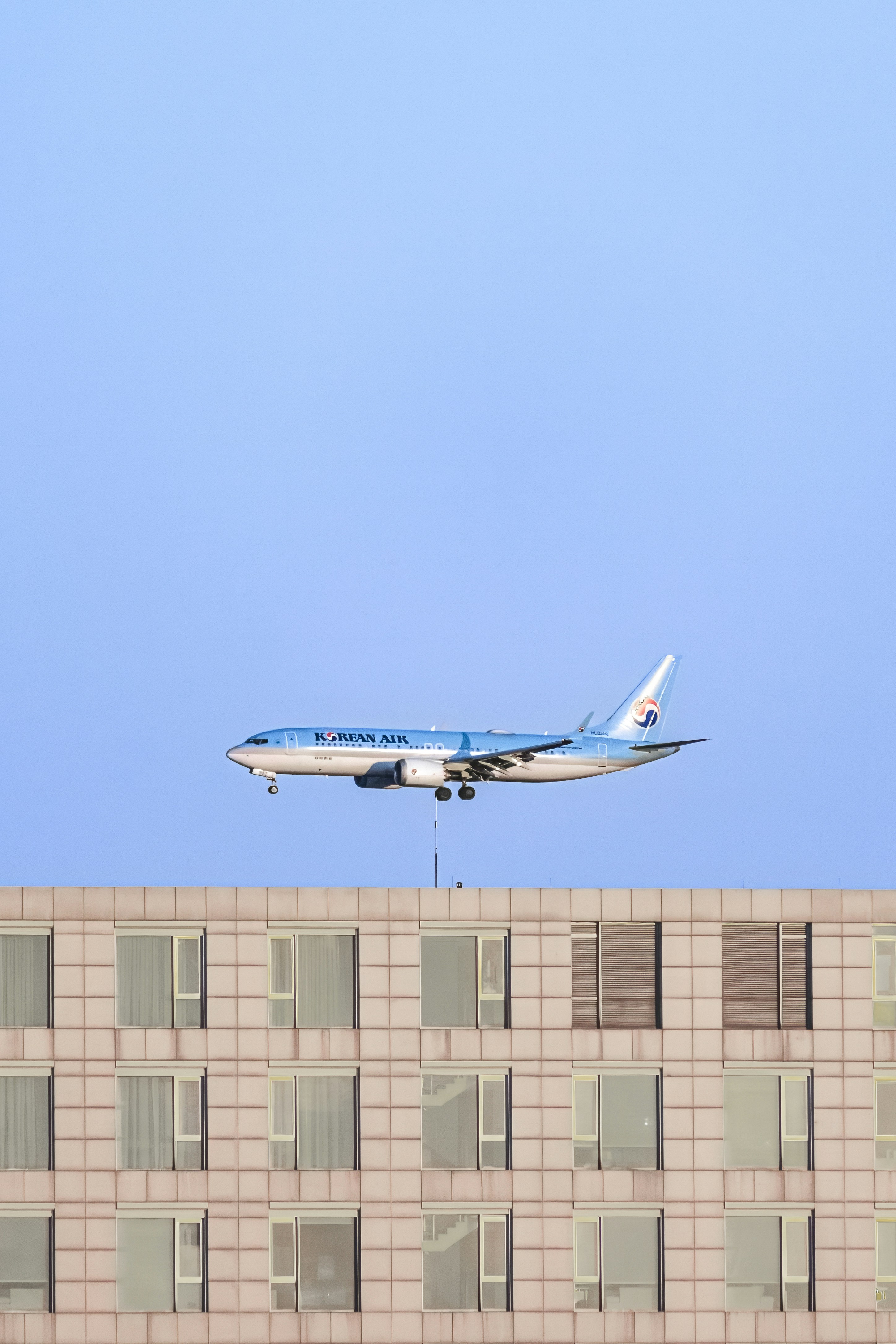 a large jetliner flying over a tall building