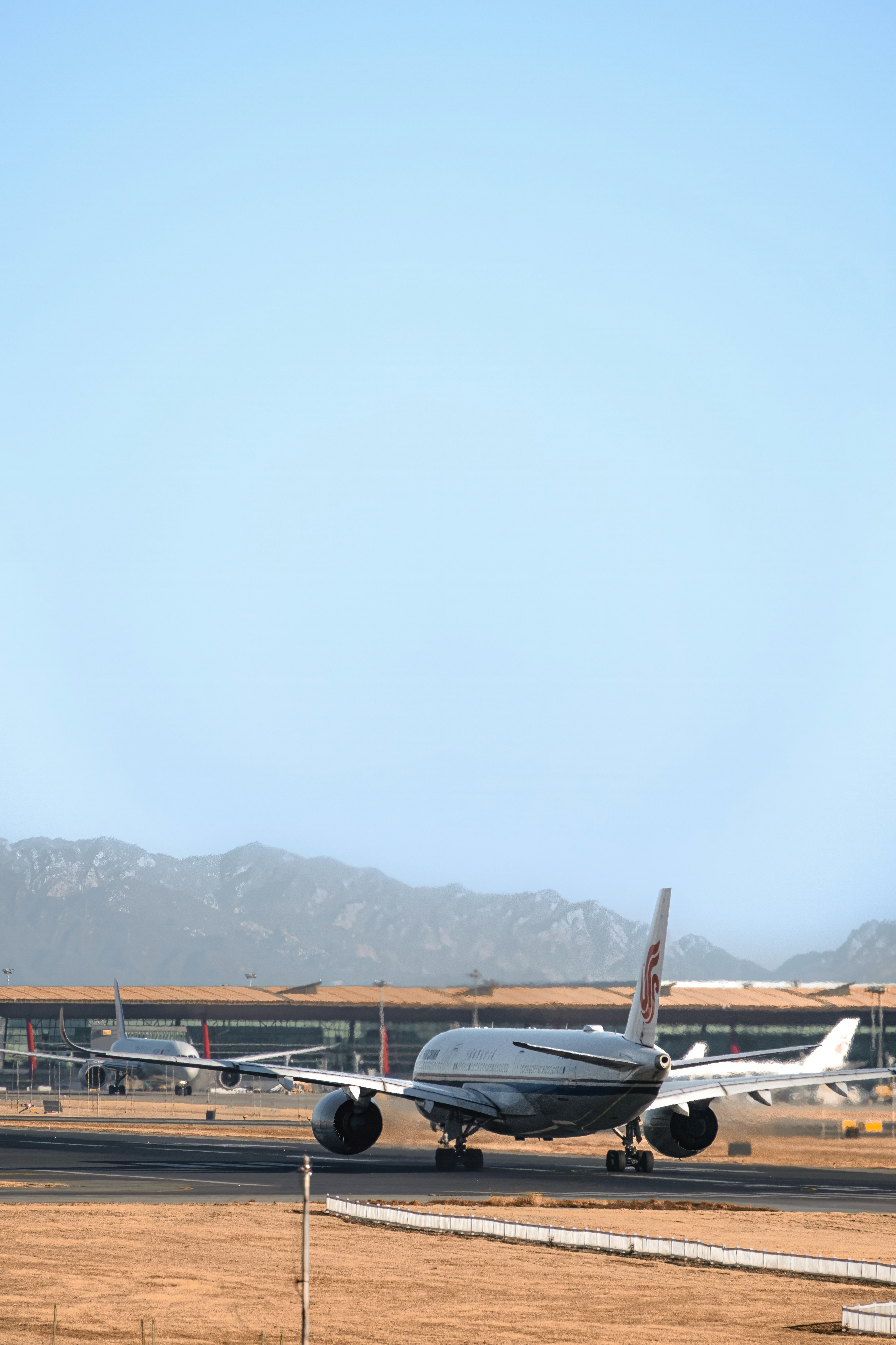 a small airplane on a run way with mountains in the background