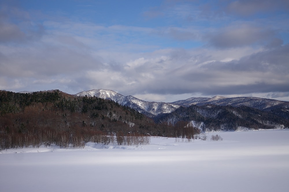 a snow covered field with mountains in the background