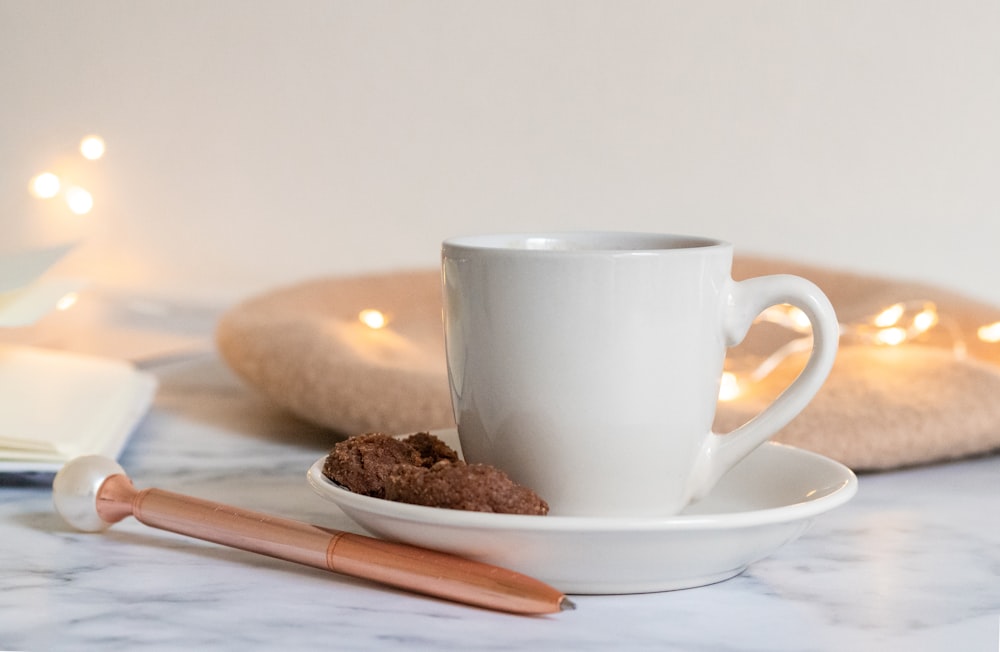 a cup of coffee on a saucer next to a cookie