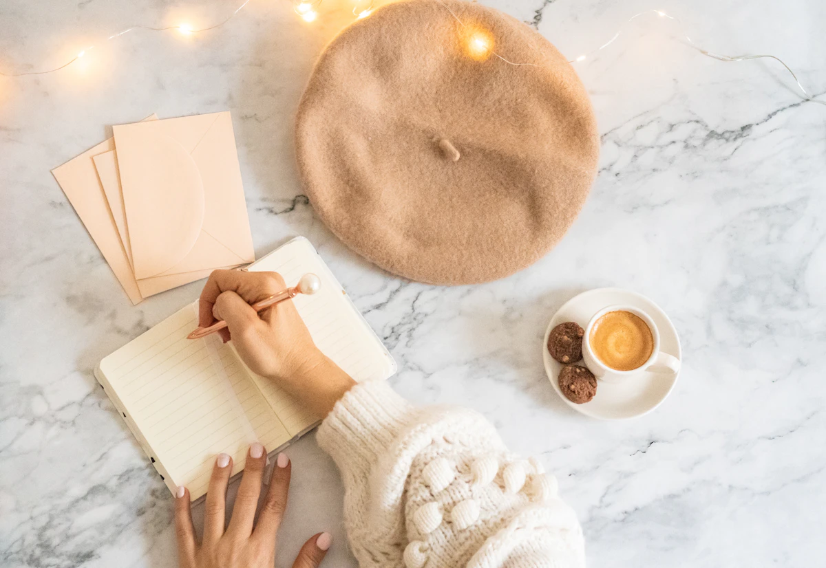 Person schreibt neben einer Tasse Kaffee in ein Notizbuch und plant neue rauchfreie Routinen