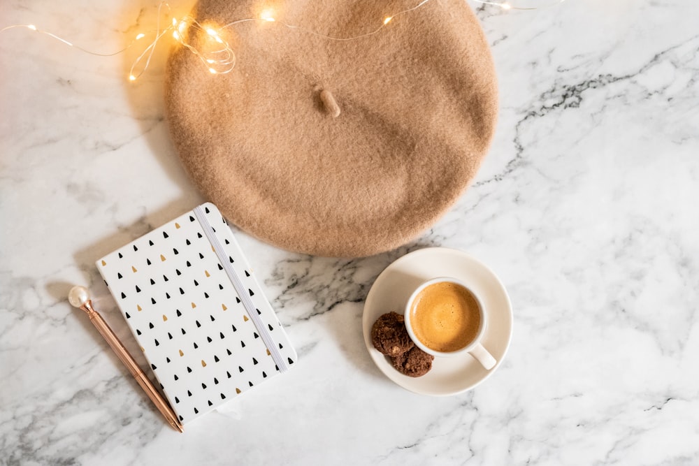 a cup of coffee next to a brown hat