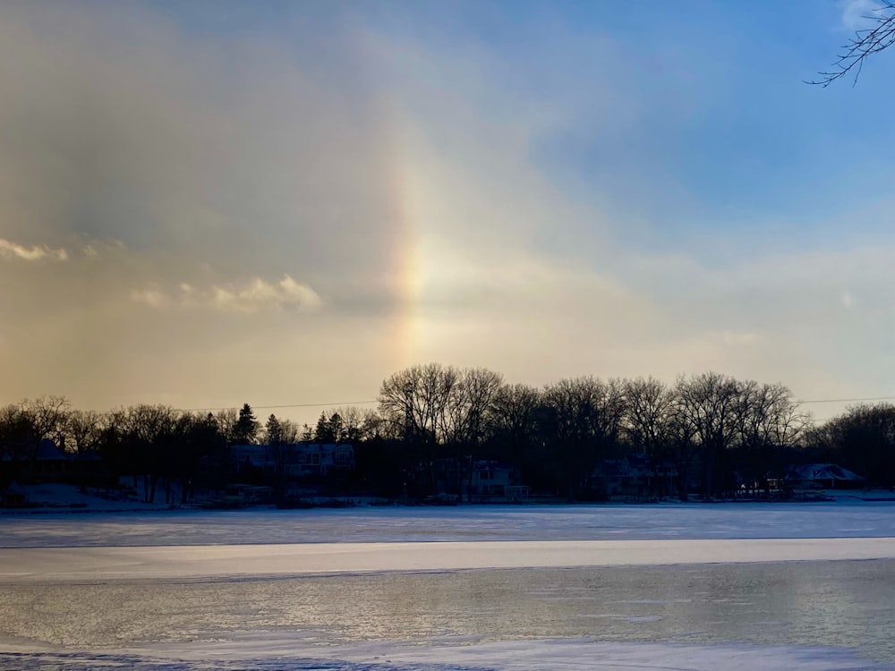 a rainbow in the sky over a frozen lake