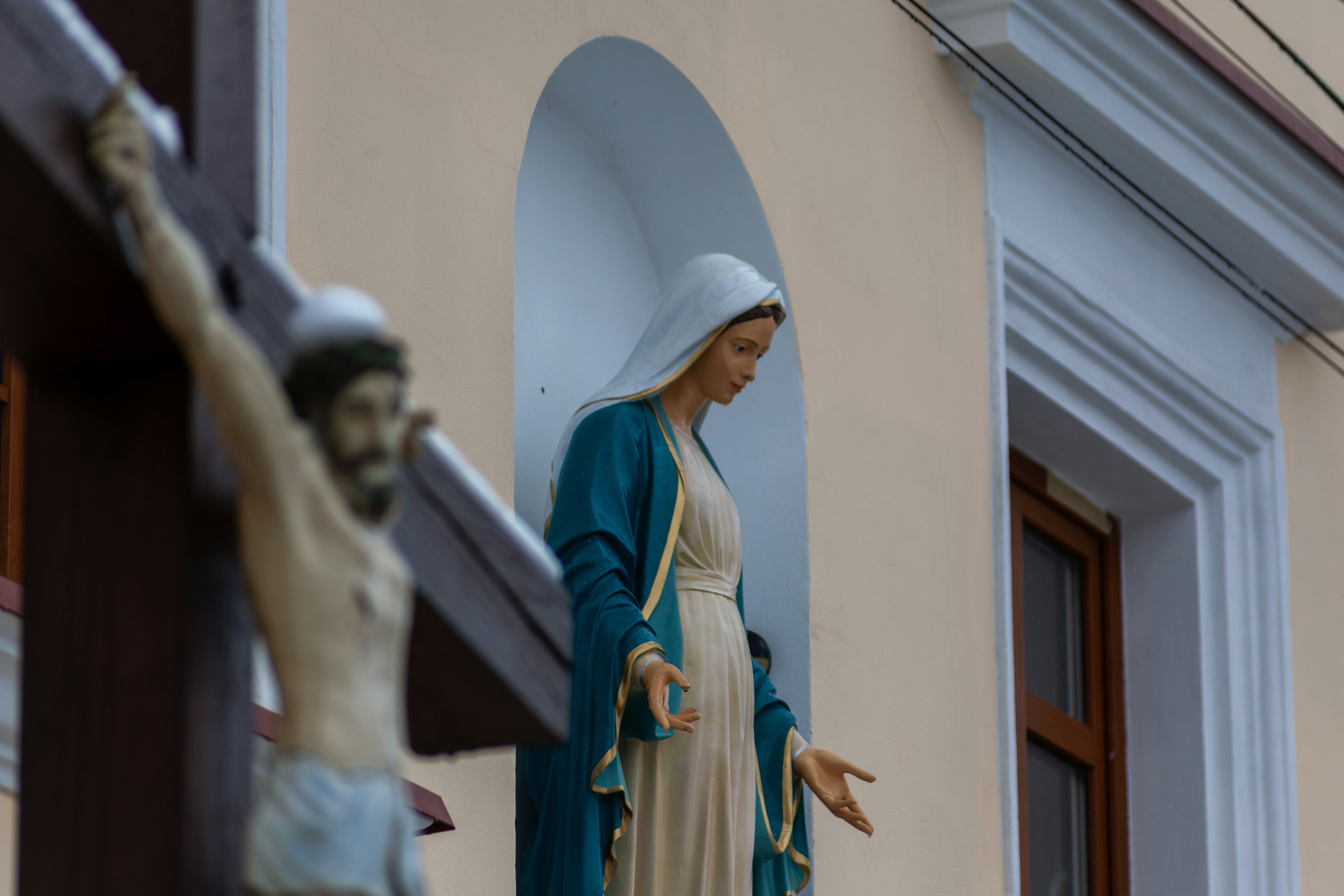 una estatua de una persona sosteniendo una cruz frente a un edificio