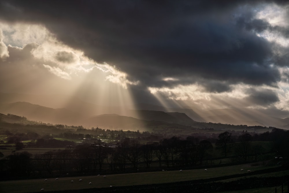 the sun is shining through the clouds over the hills