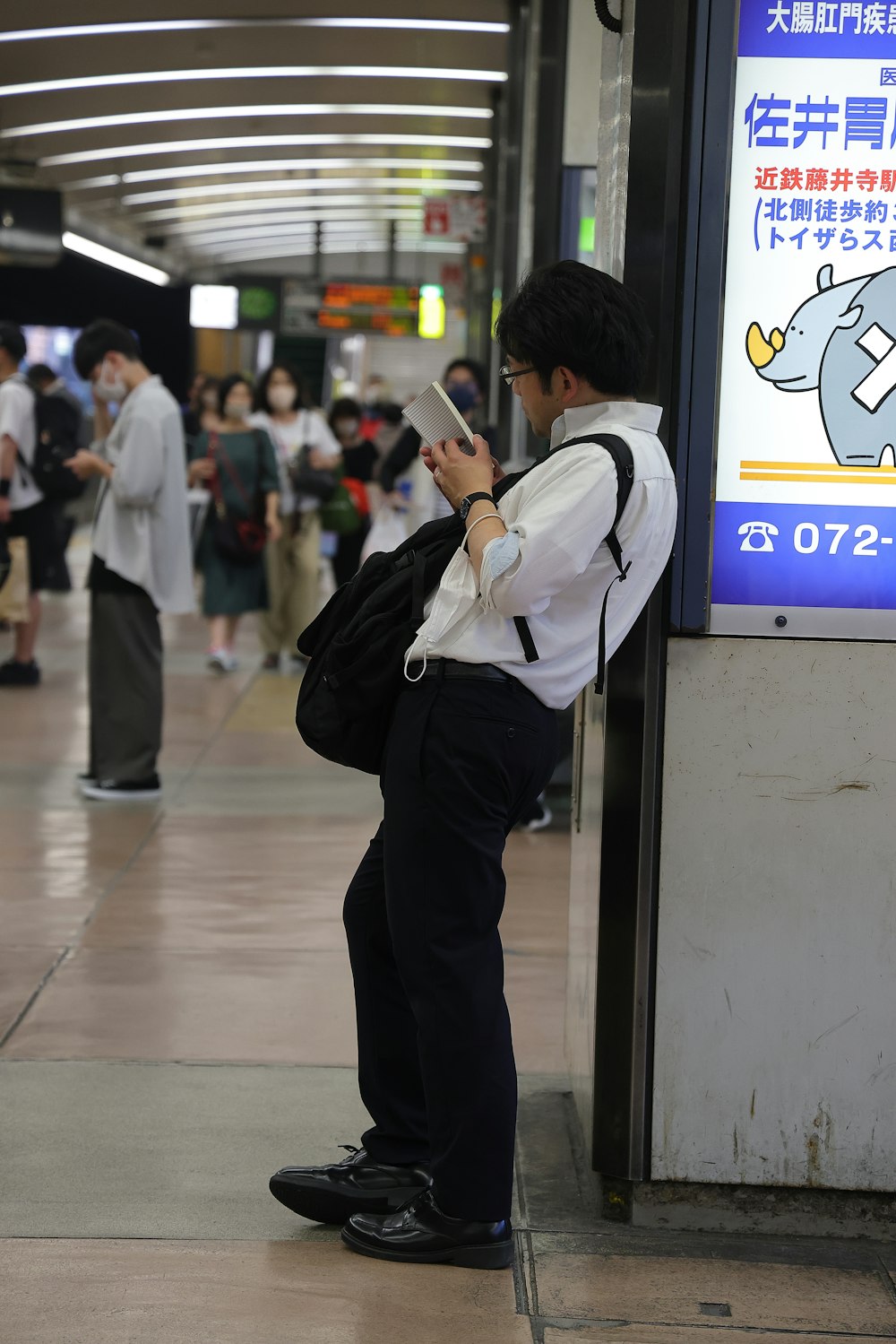 a man standing next to a train station while looking at his cell phone