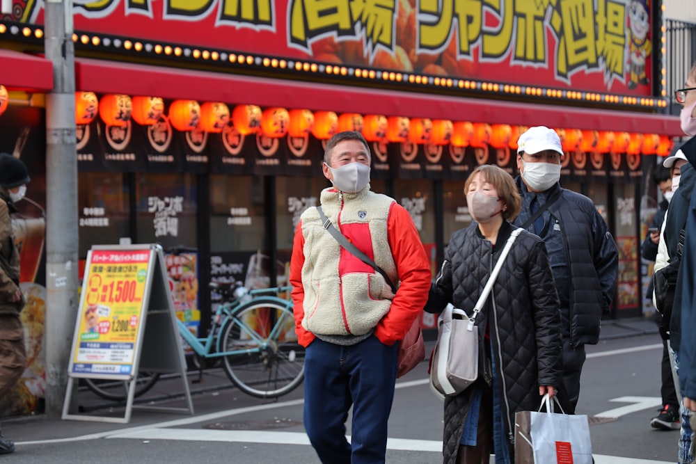 a group of people walking down a street wearing face masks