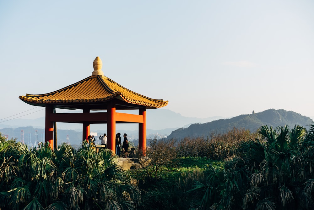 two people standing in front of a pagoda on top of a hill