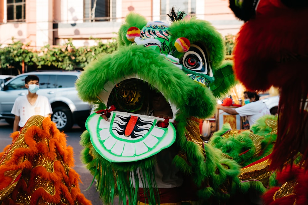 a man in a green lion costume standing next to another man in a white car