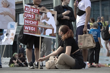a woman sitting on the ground next to a sign