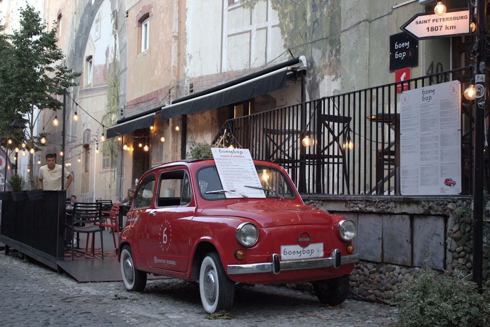 a small red car parked in front of a restaurant