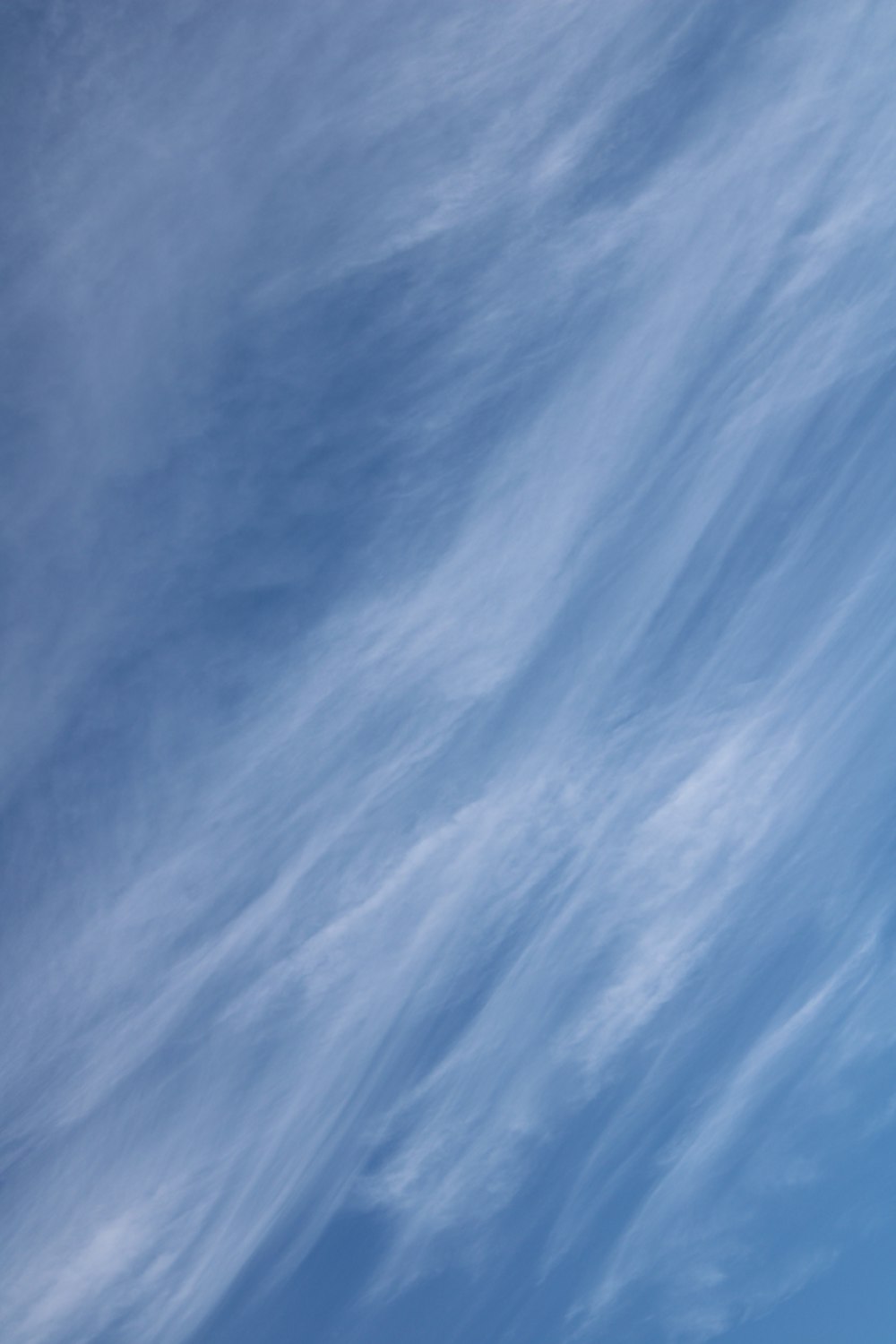 a plane flying through a blue sky with clouds