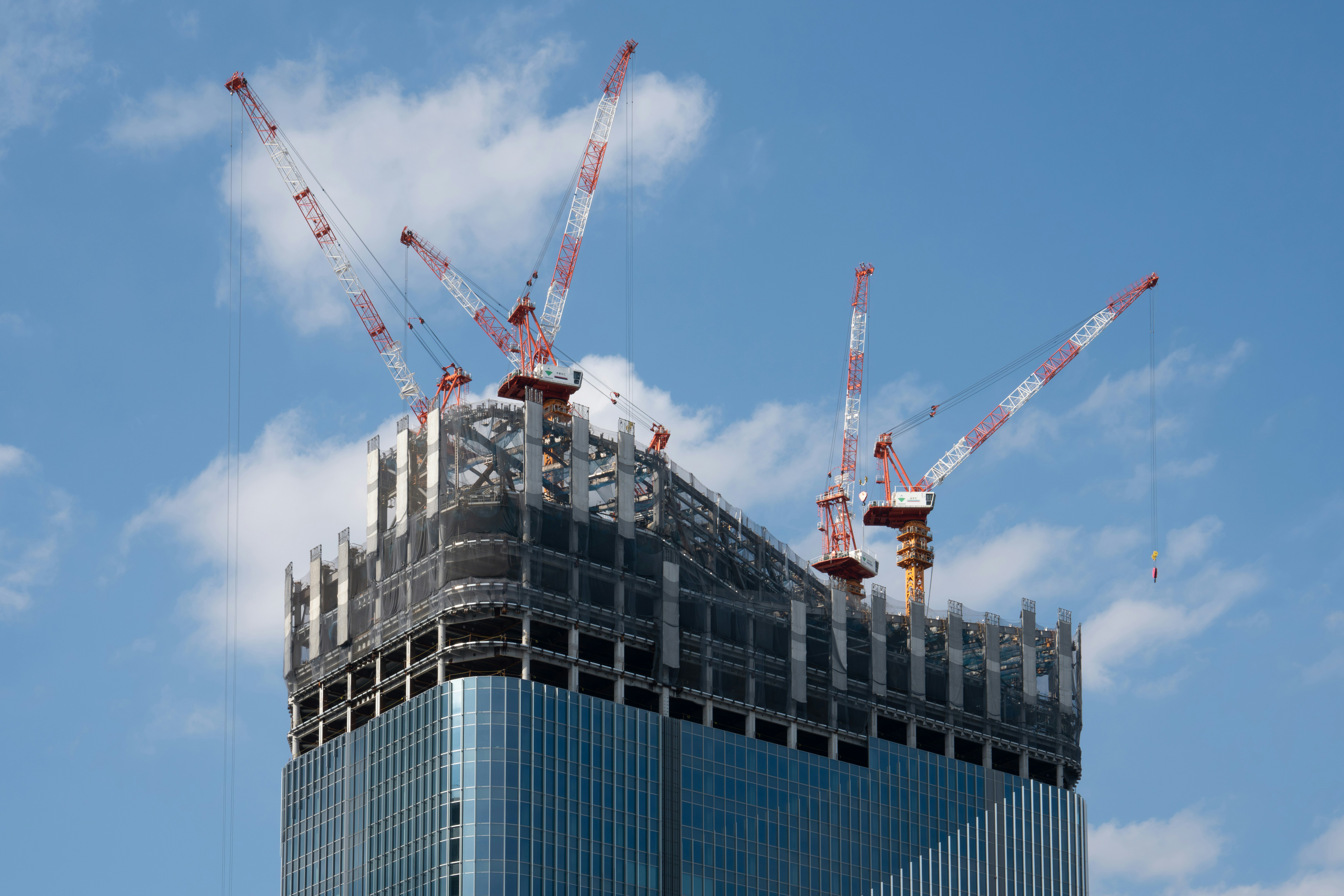 a tall building with cranes on top of it, Takanawa Gateway Construction Site: A dynamic scene of urban development with five towering cranes at the high-rise building site in Tokyo