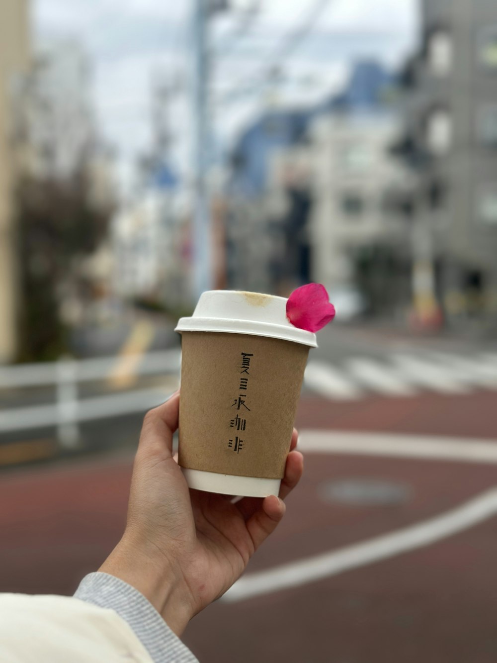 a person holding a cup of coffee with a pink flower on it