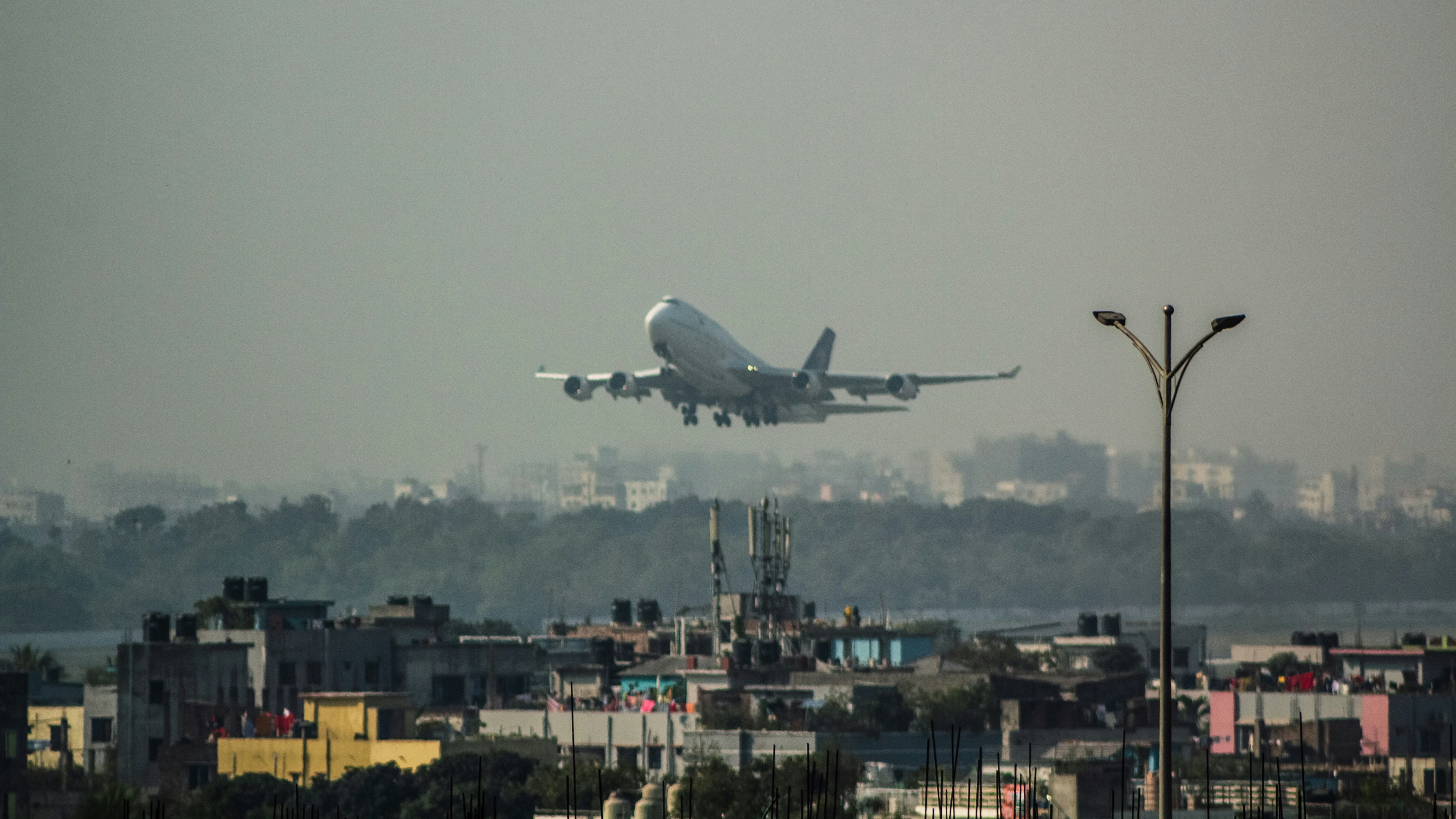 a large jetliner flying over a city, Boeing 747-400 of Saudia | 9H-AZB Dhaka - Medina.