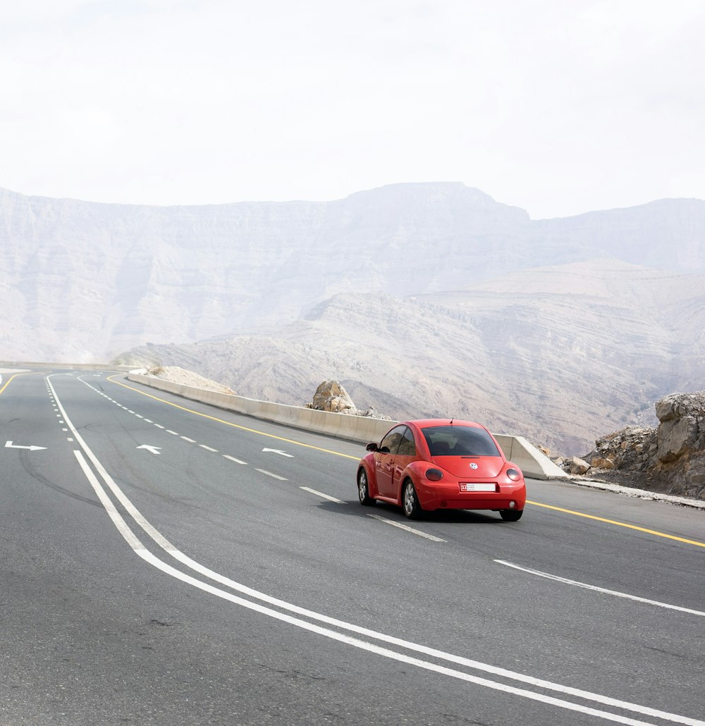 a red car driving down a mountain road