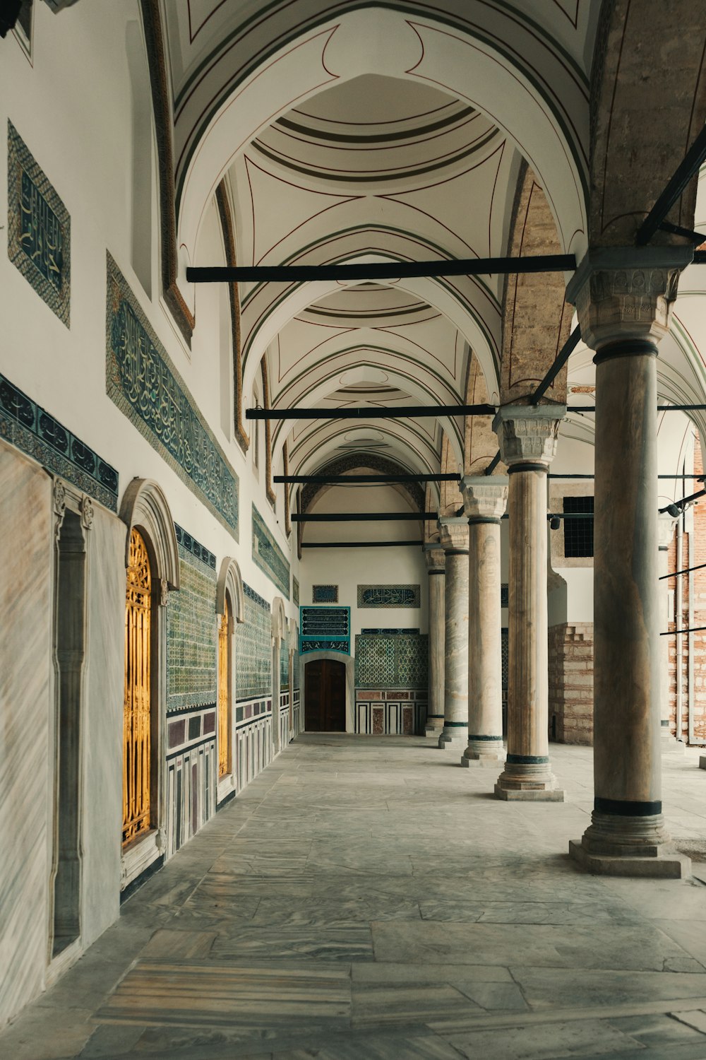 a long hallway with columns and a clock on the wall