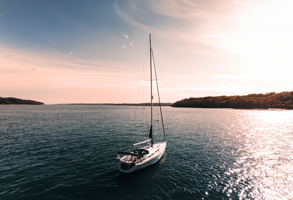 a sailboat sailing on the water at sunset