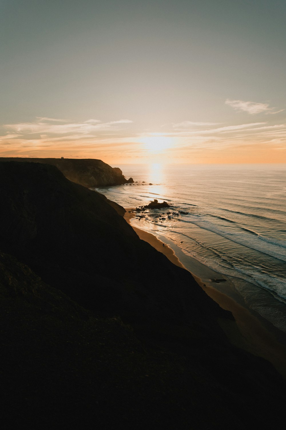 the sun is setting over the ocean on the beach