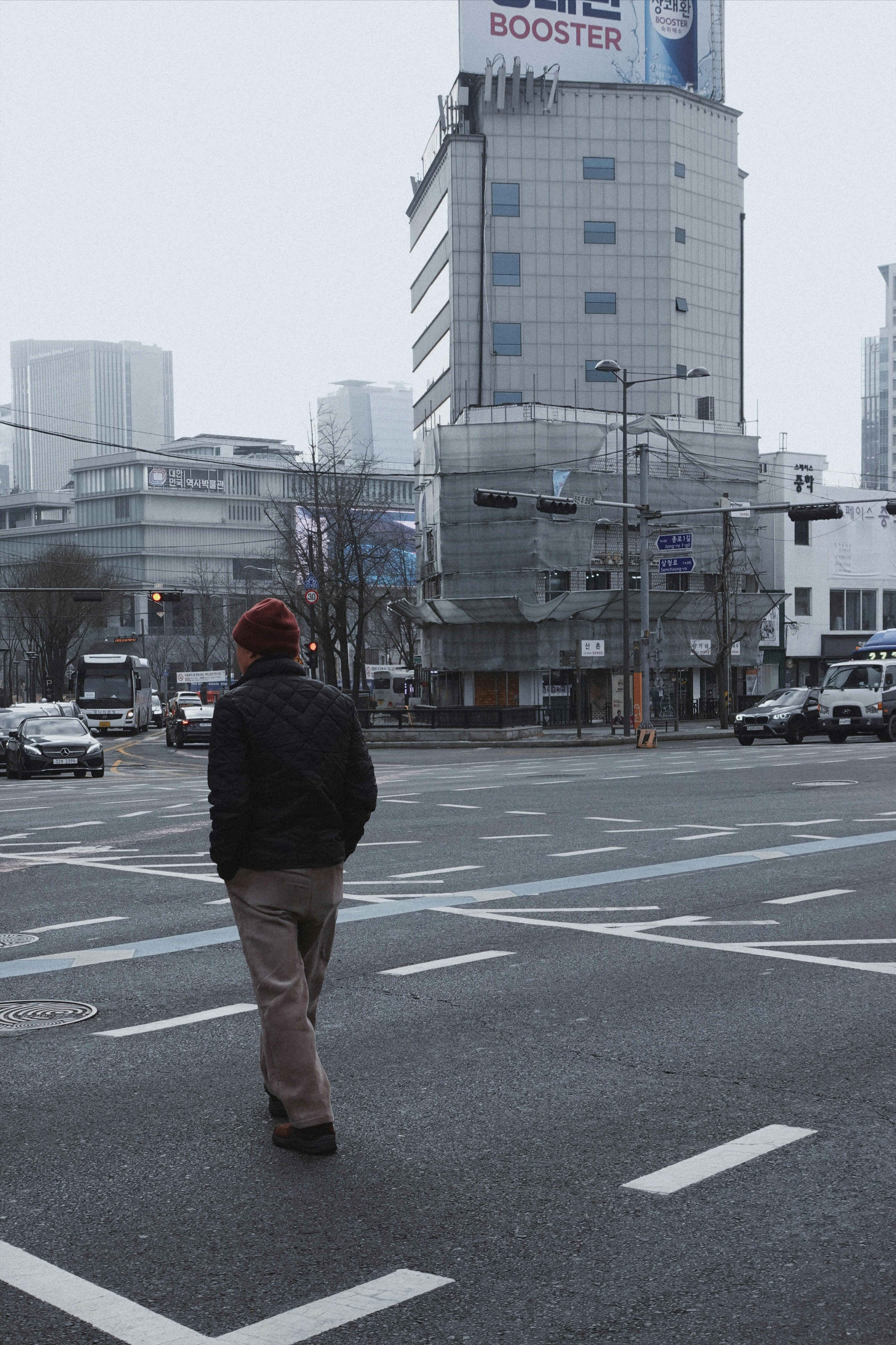a man walking across a street in front of a tall building