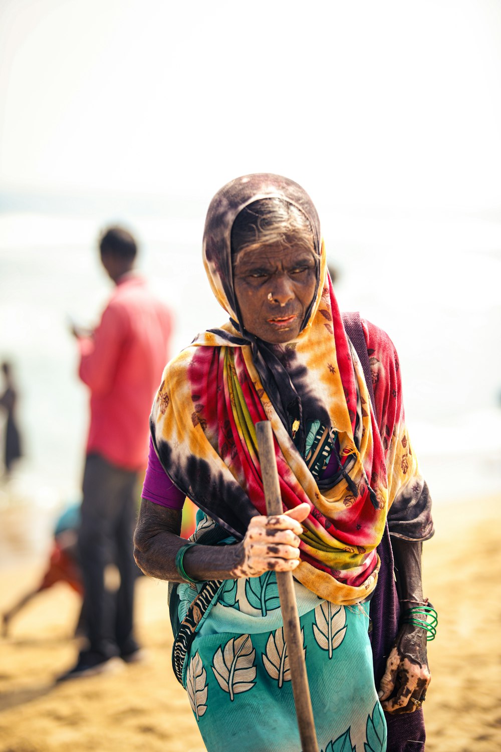 a woman standing on a beach holding a stick