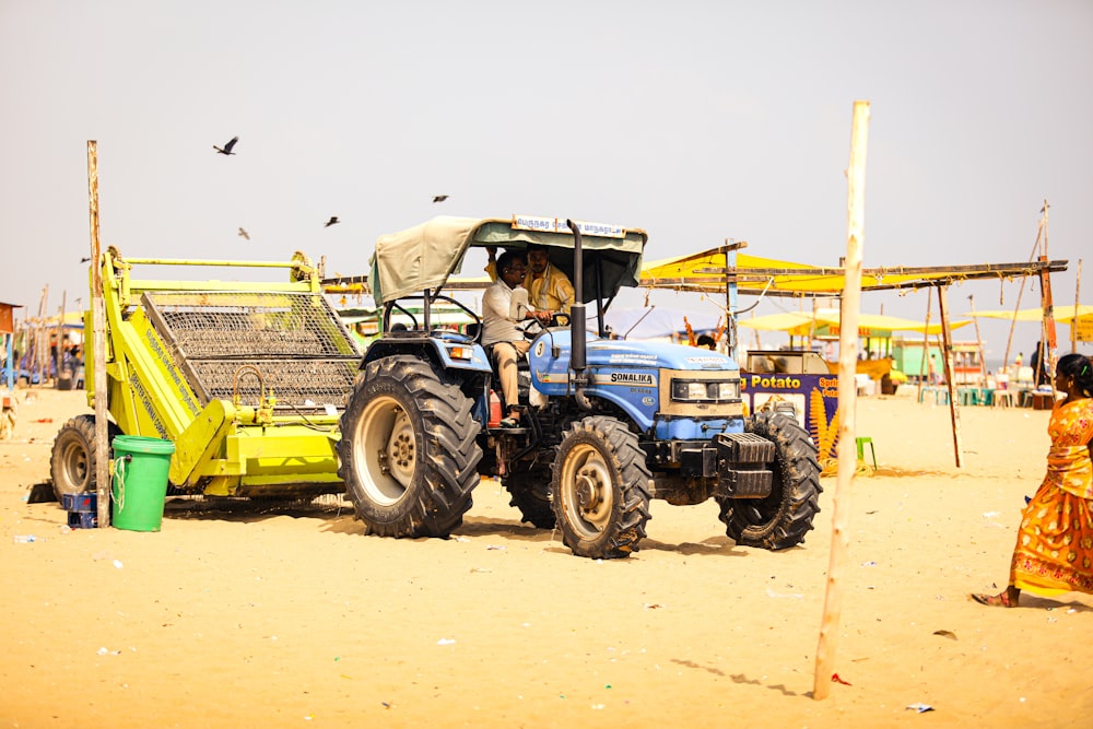 a tractor is parked on the beach with a woman standing next to it