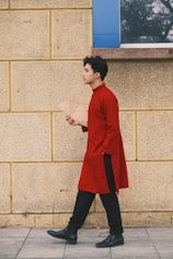 a man in a red coat is walking down the street