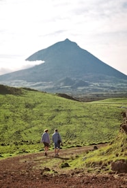 a couple of people walking down a dirt road