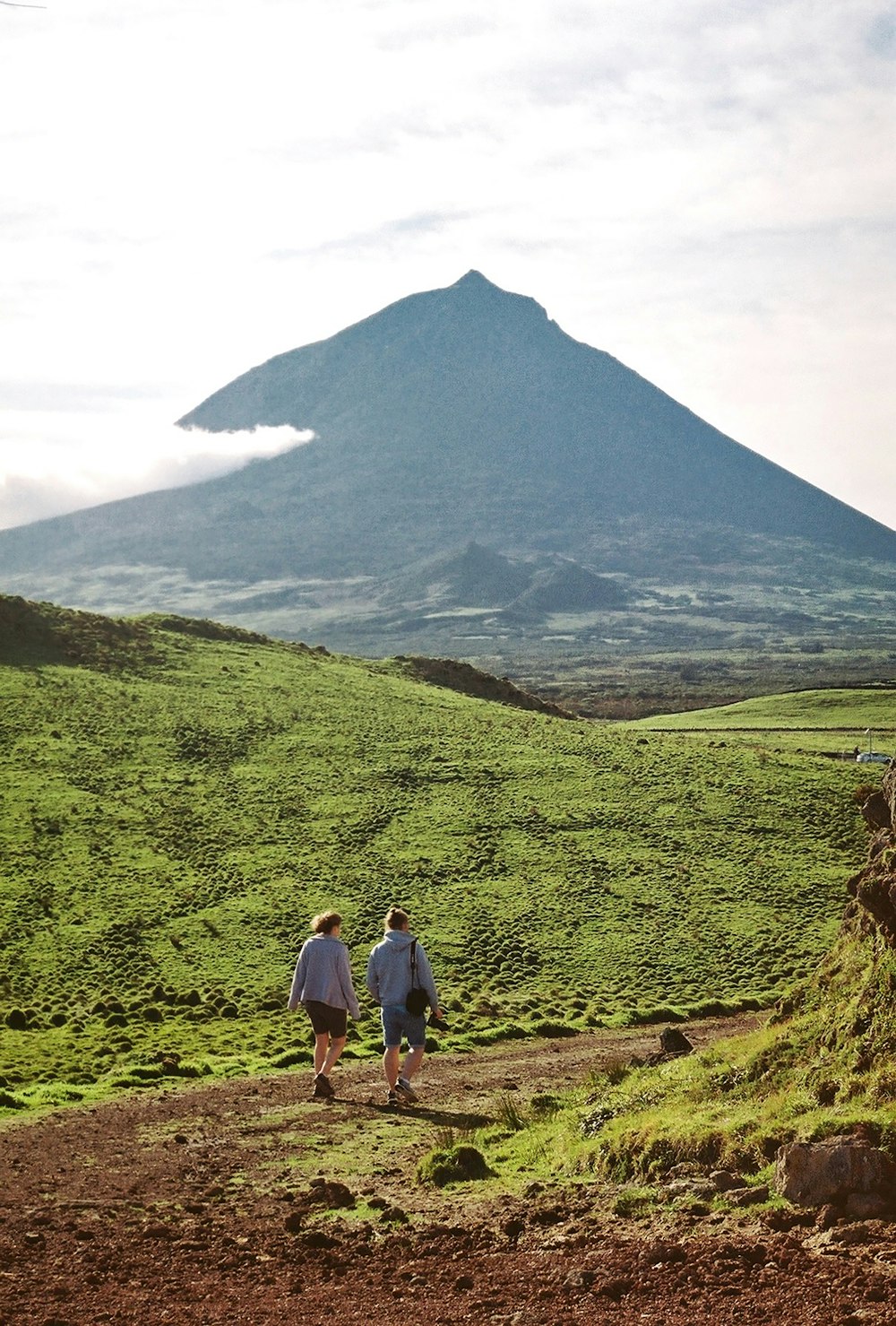 a couple of people walking down a dirt road