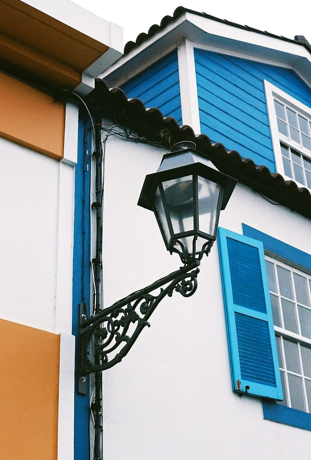 a street light next to a building with blue shutters