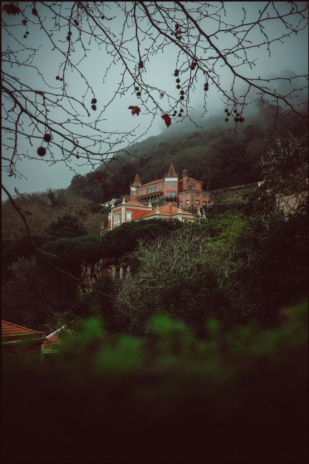 a large house sitting on top of a lush green hillside