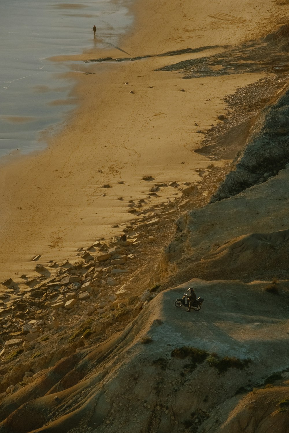 eine Person, die auf einem Motorrad an einem Sandstrand fährt