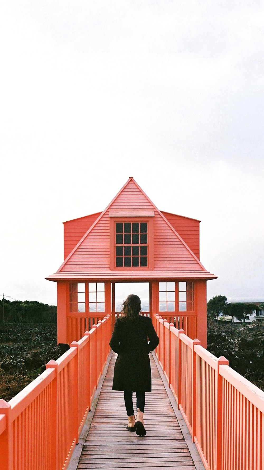 a woman walking across a bridge over a body of water