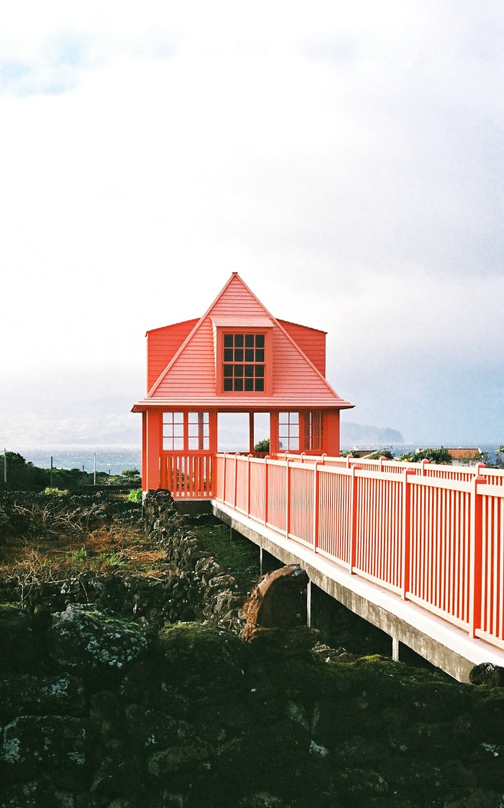una casa roja sentada en lo alto de un puente de madera