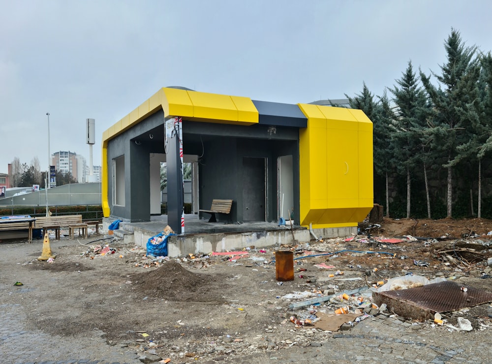 Un edificio amarillo y gris sentado en la parte superior de un campo de tierra