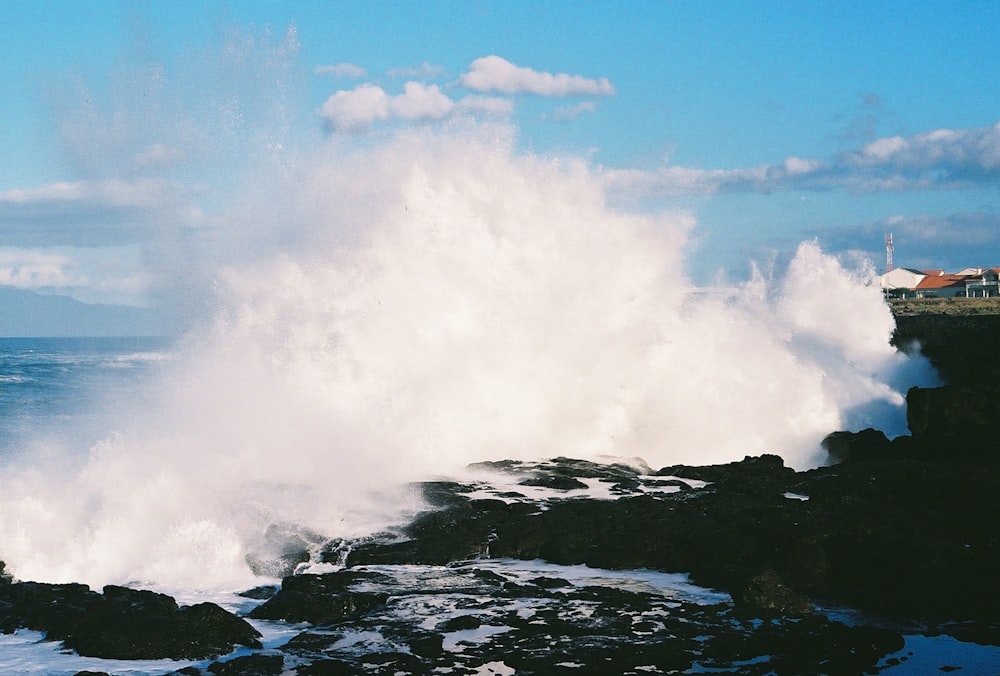 a large wave crashing into a rocky shore