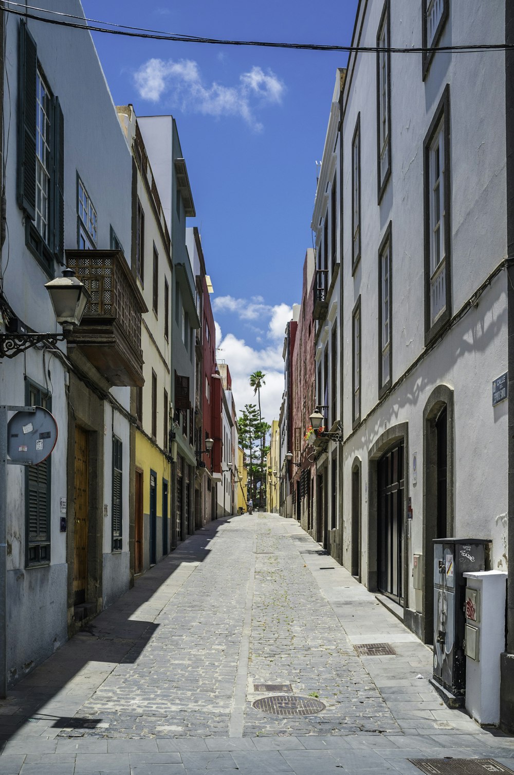 a narrow street with a clock on the side of it