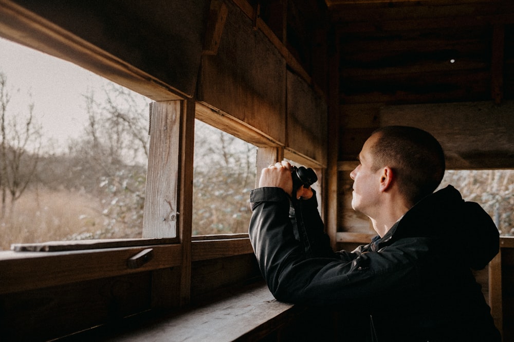 Un hombre mirando por la ventana de una cabaña