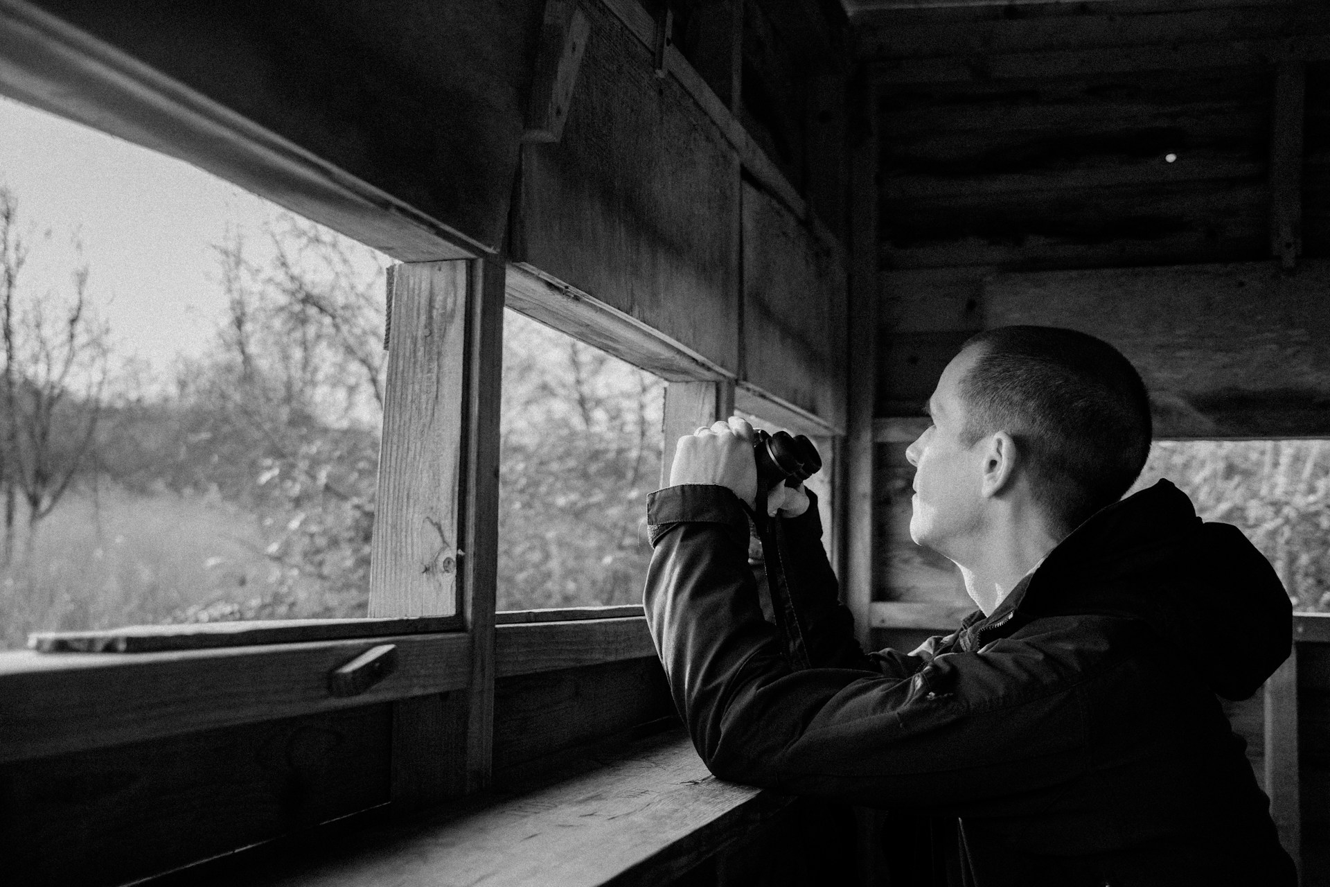 a man looking out a window at a field