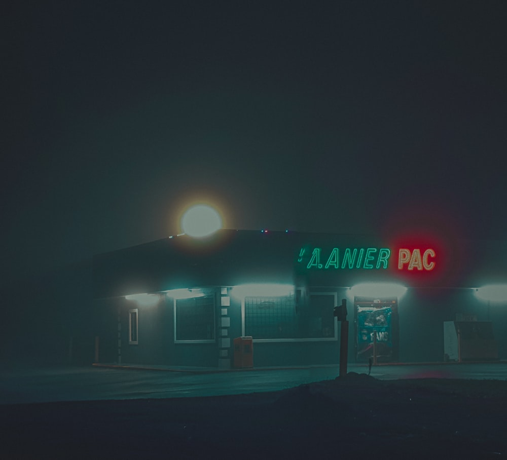 a gas station at night with a neon sign