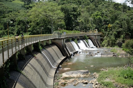 a bridge over a river with a waterfall in the background