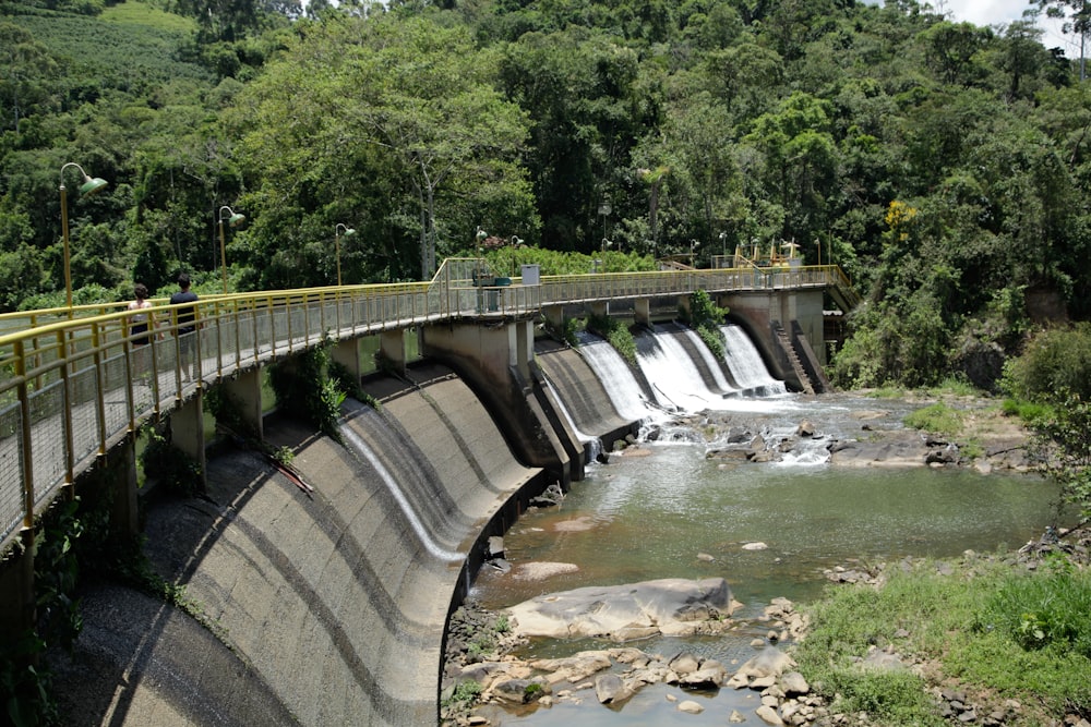 a bridge over a river with a waterfall in the background