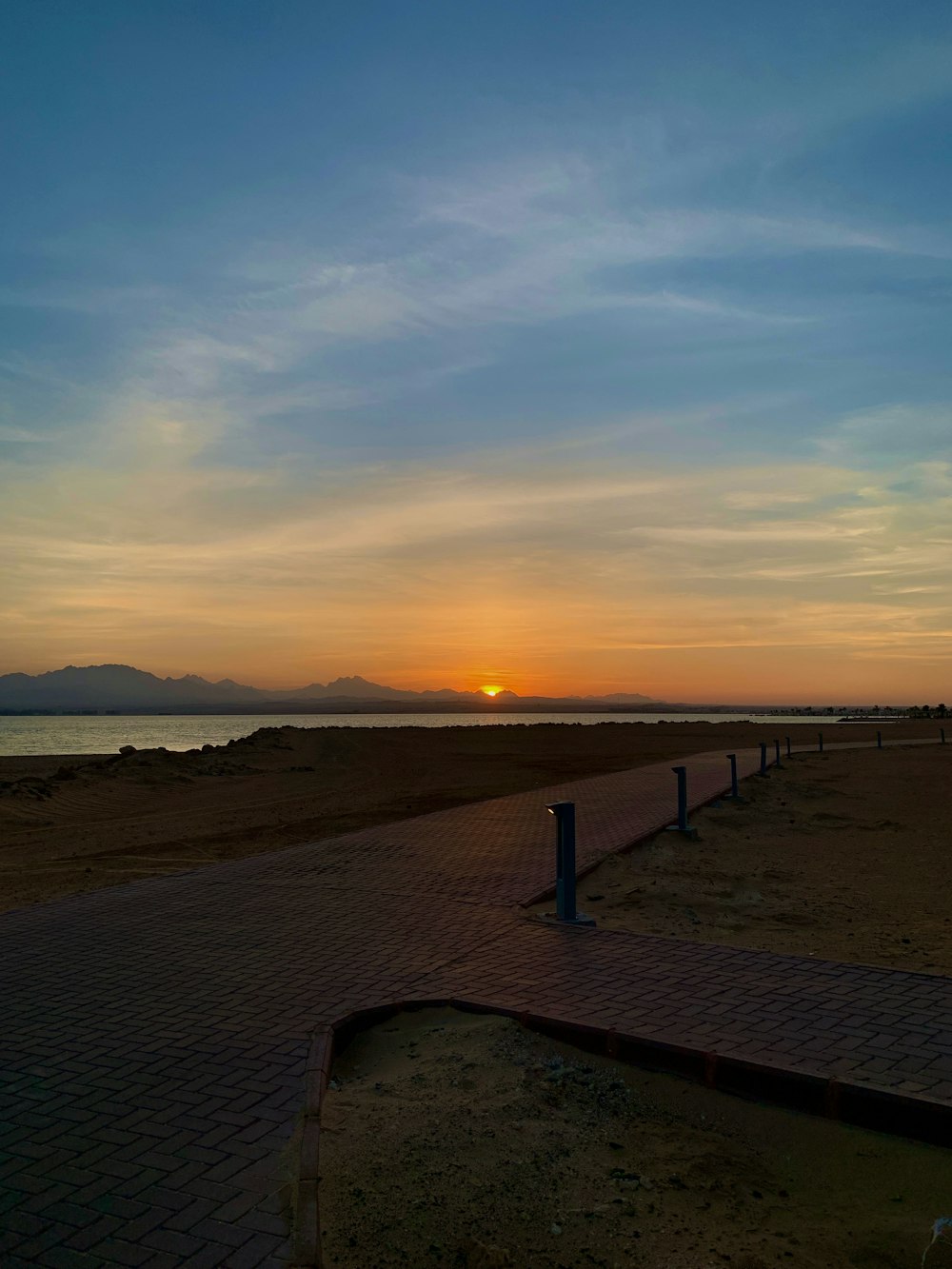 the sun is setting over the water at the beach